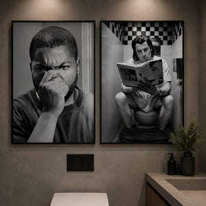 May include: Two framed black and white wall art prints displayed side by side. The left print shows a close-up of a person covering their nose with their hand. The right print depicts a person sitting on a toilet reading a book in a tiled room.