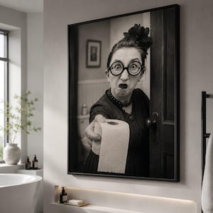 May include: A black and white framed wall art print depicting a person with dark hair in an updo, wearing round glasses and a dark dress, holding out a roll of toilet paper. The person has a surprised expression with wide eyes and dark lips.