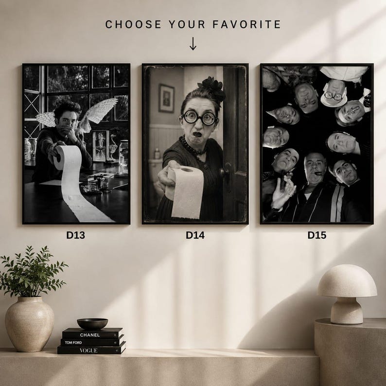May include: Three black and white framed wall art prints labelled D13, D14, and D15. D13 shows a person holding a toilet paper roll. D14 shows a person with glasses holding a toilet paper roll. D15 shows a group of people looking down in a circle.
