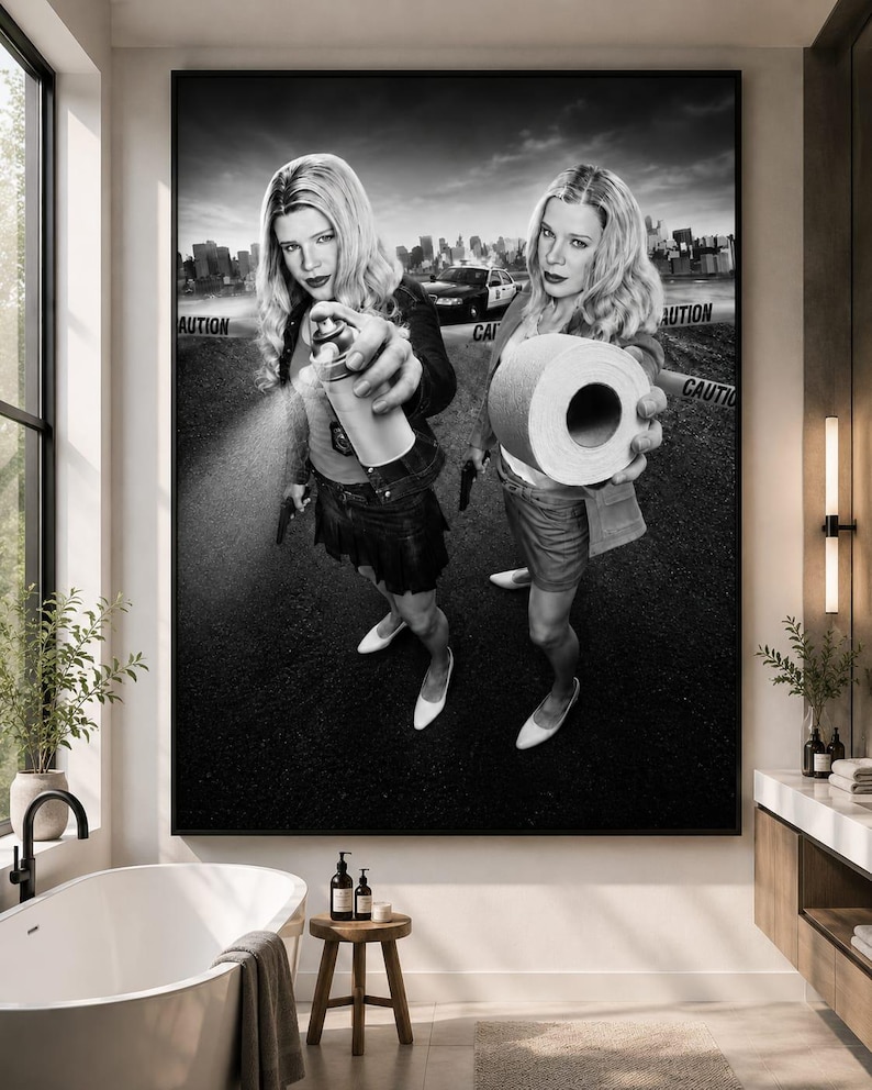 May include: A black and white wall art print depicting two identical blonde figures standing on asphalt. One figure holds a spray paint can, while the other holds a roll of toilet paper. A police car and caution tape are visible in the background.