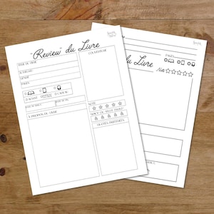 May include: Two white paper sheets with the text "Review du Livre" and other French text. The sheets have spaces for writing a book review, including sections for title, author, genre, and notes. The sheets are on a wooden surface.