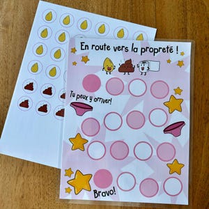 Puede incluir: Una tabla de recompensas para el entrenamiento de ir al baño con el texto en francés En route vers la propreté, Tu peux y arriver y Bravo. Incluye ilustraciones de gotas amarillas, un personaje de excremento, papel higiénico y ropa interior rosa.