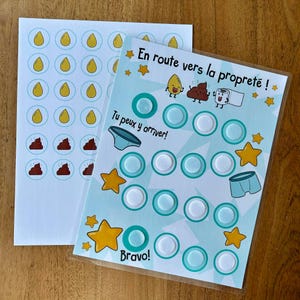 May include: A potty training reward chart with light blue background, yellow stars, and illustrations of a drop, poop, and toilet paper. It features the text En route vers la proprete, Tu peux y arriver, and Bravo, with circular velcro spots.