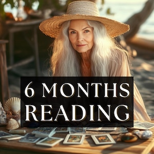 Op de afbeelding: Een oudere vrouw met lang grijs haar en een strohoed zit aan een houten tafel op het strand. Op de tafel liggen tarotkaarten, schelpen en een bord met de tekst "6 MONTHS READING". De scène wordt verlicht door natuurlijk licht.