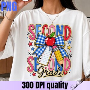 Peut inclure: Un t-shirt blanc avec un motif graphique portant l'inscription "SECOND GRADE" en grandes lettres roses et bleues. Le centre comprend un nœud à carreaux bleu et blanc, une pomme rouge, un crayon jaune et une feuille de papier ligné.