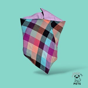 Può includere: Un bandana reversibile per animali domestici con un vivace motivo a quadri nei toni del viola, rosa, blu e arancione. L'interno è in tessuto lavanda tinta unita. Prodotto da Josie.inc PETS.