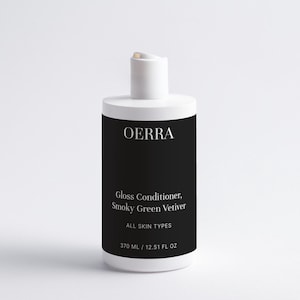 May include: A white bottle of OERRA Gloss Conditioner, Smoky Green Vetiver, for all skin types. The bottle has a black label with white text and a white cap. The bottle contains 12.51 fl oz.