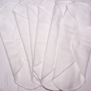 May include: Five white reusable cloth menstrual pads with a snap closure.
