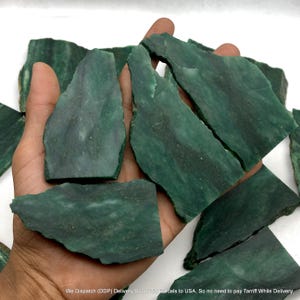 Può includere: Una collezione di lastre di pietra verde scuro, piatte e di forma irregolare, con venature naturali visibili e superfici lisce. Questi pezzi minerali mostrano varie tonalità di verde bosco e verde smeraldo intenso.