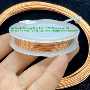 May include: A spool of copper wire is held in a hand, with a coil of wire in the background. The spool is white and contains tightly wound, shiny copper wire. Text on the spool reads: "We Sends Delivery Duty Paid (DDP) Parcels to USA So You No Need To Pay Any Tariff Charges While Delivery!"