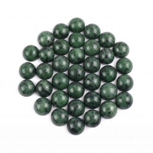 Può includere: Una collezione di trentuno cabochon lisci, rotondi e levigati, caratterizzati da un colore verde bosco profondo con scure inclusioni nere maculate in ogni pietra, disposti in un denso gruppo circolare su uno sfondo bianco uniforme.