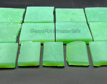 May include: A collection of thirteen rectangular light green translucent stone slabs arranged in rows. The pieces have smooth surfaces and irregular edges. The text GemsRAWmaterials is printed in the center of the arrangement.