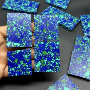 Könnte beinhalten: Eine Sammlung rechteckiger und quadratischer Lapis-Lazuli-Steine. Die Steine weisen eine tiefblaue Grundfarbe mit einem gesprenkelten Muster aus grünen und helleren Blautönen auf. Der Text "GemsRAWmaterials" ist sichtbar.