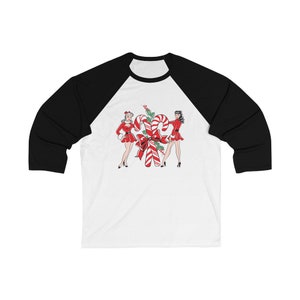 May include: A white and black baseball tee shirt with a Christmas-themed design featuring two women in red dresses standing next to a large candy cane.