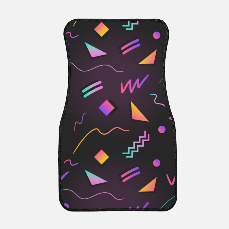 May include: A black car floor mat with a geometric pattern in pink, blue, yellow, and orange. The pattern includes triangles, squares, and wavy lines.