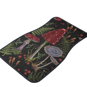 May include: A black doormat with a repeating pattern of red and white mushrooms, green ferns, and red berries. The doormat has a navy blue border.