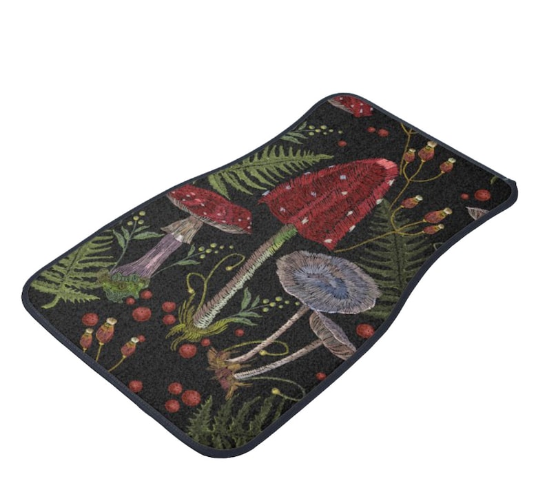 May include: A black doormat with a repeating pattern of red and white mushrooms, green ferns, and red berries. The doormat has a navy blue border.