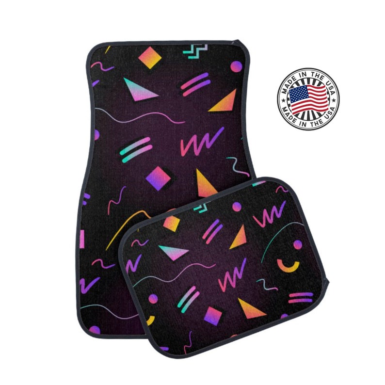 May include: A set of two car floor mats with a geometric pattern in shades of pink, purple, yellow, and blue on a black background. The mats have a black border.