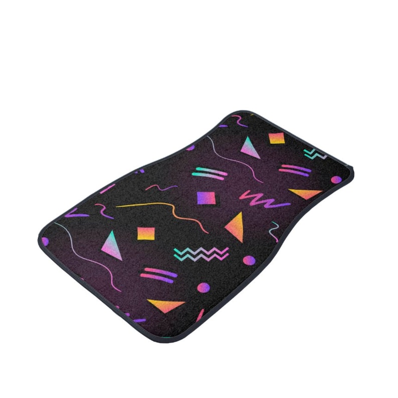 May include: A black car floor mat with a geometric pattern in pink, yellow, blue, and purple. The pattern includes triangles, squares, circles, and wavy lines.