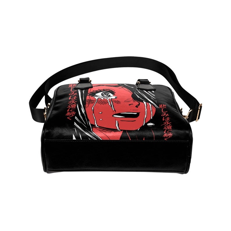 May include: Black shoulder bag featuring a red illustration of a crying face with white hair. The bag has a black strap and handles, with gold-colored hardware. Japanese text is printed on the side of the bag.