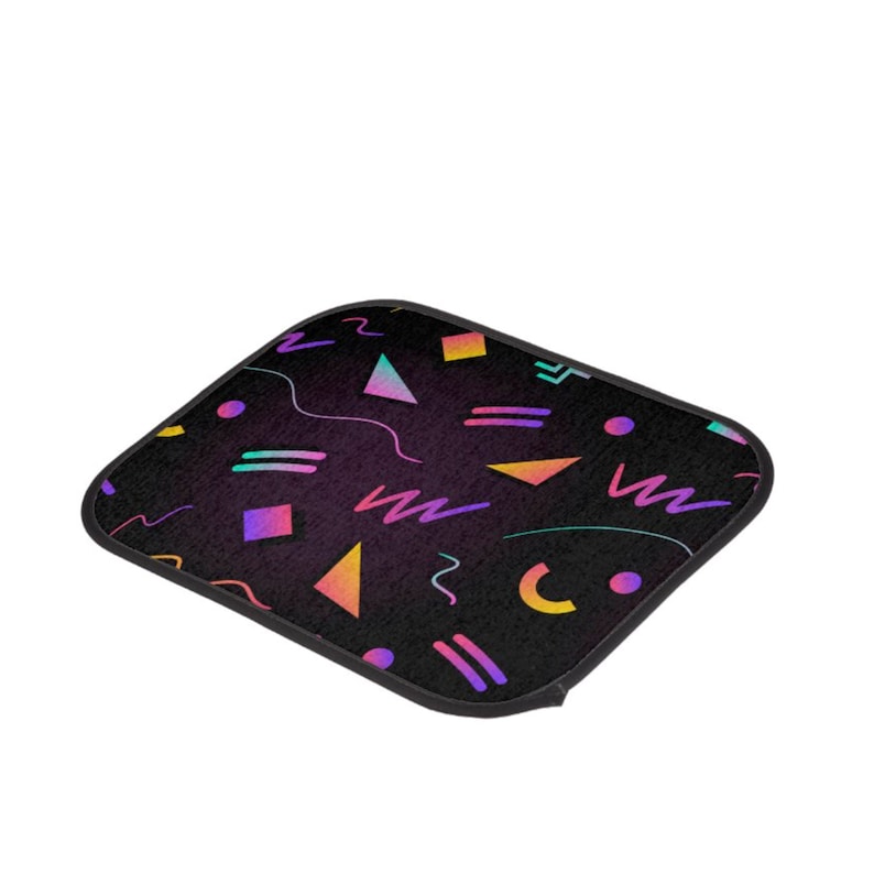 May include: A black car floor mat with a geometric pattern in pink, purple, yellow, and blue. The pattern includes triangles, squares, circles, and wavy lines.