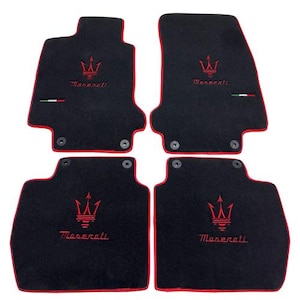May include: Set of four black car floor mats with red trim. Each mat features a red Maserati logo and the brand name embroidered in red. Includes the Italian flag colors.