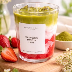Könnte beinhalten: Geschichtete Kerze in einem klaren Glas, mit roten, weißen und grünen Abschnitten, die einem Matcha Latte ähneln. Auf dem Etikett steht "Strawberry Matcha Latte". Sojawachs, handgegossen und vegan. Die Kerze hat 300 ml.