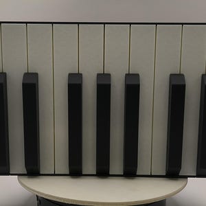 May include: A rectangular wall art piece featuring a piano keyboard design. The artwork has a black frame, with black keys and off-white background. The keys are evenly spaced and create a minimalist aesthetic.