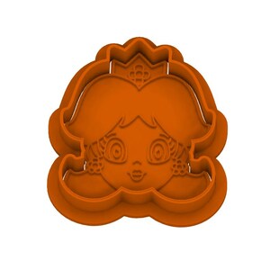 May include: An orange plastic cookie cutter shaped like a cartoon character with a crown, large eyes, and flower-shaped earrings. The design features a raised outline for the face, hair, and crown details, creating a clear impression for baking.