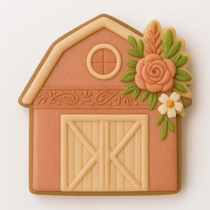 May include: A gingerbread cookie shaped like a barn, decorated with peach-colored icing and floral accents. The barn features a round window, a detailed door, and a decorative border. A large peach rose and small white flower adorn the roof.