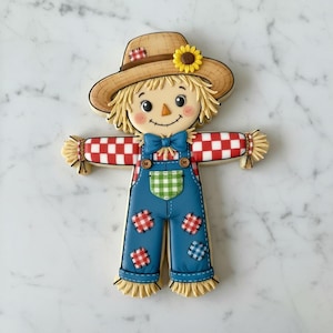 May include: A scarecrow-shaped sugar cookie decorated with royal icing. The figure wears a tan hat with a yellow sunflower, a red and white checkered shirt, a blue bowtie, and blue overalls featuring red and blue checkered patches.