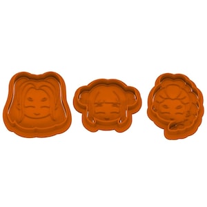 May include: Three orange plastic cookie cutters in the shape of stylized faces. Each cutter has a different hairstyle, including long flowing hair, bangs, and a braided style. The faces have closed eyes and a small smile.