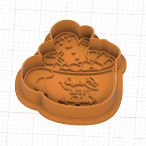 Puede incluir: Un cortador de galletas naranja con forma de taza llena de malvaviscos y un hombre de jengibre. El frente de la taza presenta el texto en relieve Baby It's Cold Outside. El cortador tiene un borde elevado y una base plana para la masa.