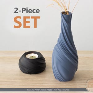 May include: A two-piece set comprising a blue vase with a spiral design and a black candle holder. The vase contains dried ornamental grass. The image displays the text "2-Piece SET".