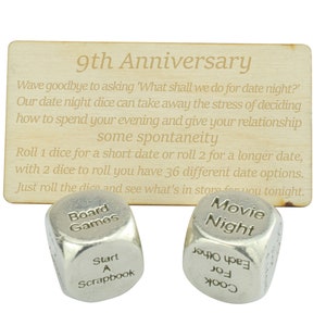 May include: A wooden plaque with the text "9th Anniversary" and instructions for date night dice. Two silver dice are labeled "Board Games", "Start A Scrapbook", "Movie Night", and "Cook For Each Other".