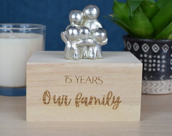 May include: A wooden box with a silver family figurine on top. The box is engraved with the text "15 YEARS Our family".