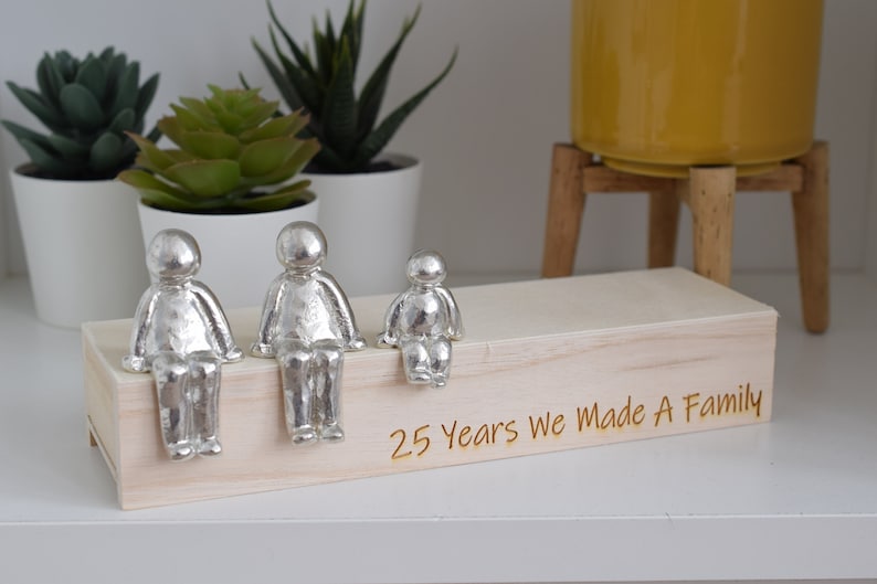 a Handmade tin family scene in 2 adults and children in a wooden box with straw is one of the best gift for 25th anniversary gift for parents