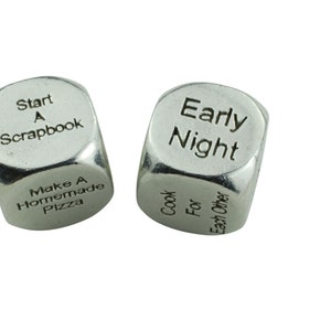 May include: Two silver metal dice with different phrases on each side. One die reads "Start A Scrapbook" and "Make A Homemade Pizza". The other die reads "Early Night" and "Cook For Each Other".