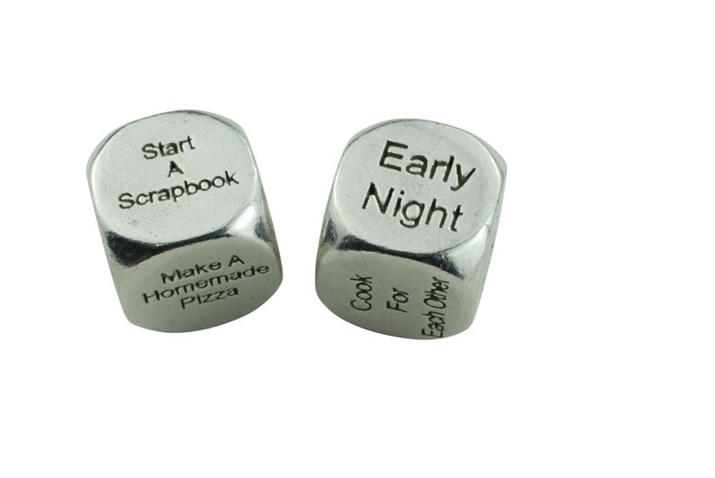 May include: Two silver metal dice with different phrases on each side. One die reads "Start A Scrapbook" and "Make A Homemade Pizza". The other die reads "Early Night" and "Cook For Each Other".