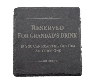 Puede incluir: Un posavasos de pizarra negra con el texto "Reservado para la bebida de Abuelo. Si puedes leer esto, tráele otro."