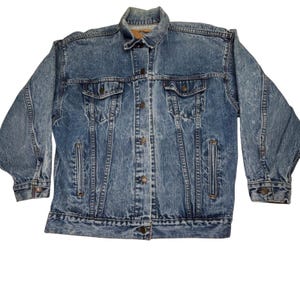 May include: A vintage blue denim jacket with a button-up front, two chest pockets, and two side pockets. The jacket has a classic collar and long sleeves with buttoned cuffs. The denim has a faded, worn look.