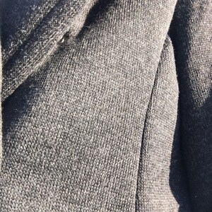 May include: Close-up of a dark gray knitted fabric with a subtle texture. The fabric is soft and appears to be made of a high-quality material.