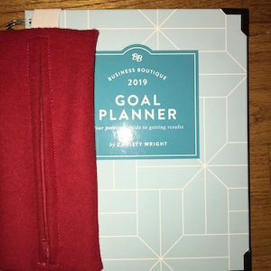 Peut inclure: Un agenda bleu et blanc avec le texte "Business Boutique 2019 Goal Planner Your personal guide to getting results by Christy Wright" sur la couverture.