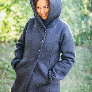 May include: A dark gray hooded jacket with a button closure. The jacket has a relaxed fit and a soft, textured fabric.