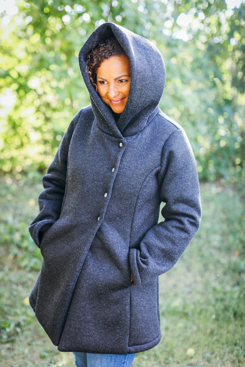 May include: A dark gray hooded jacket with a button closure. The jacket has a relaxed fit and a soft, textured fabric.