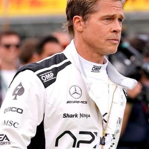 Puede incluir: Chaqueta de carreras blanca con detalles negros, con logotipos de OMP, AMG, Shark Ninja y AP. La chaqueta tiene una cremallera dorada y la lleva una persona con cabello casta&ntilde;o claro.