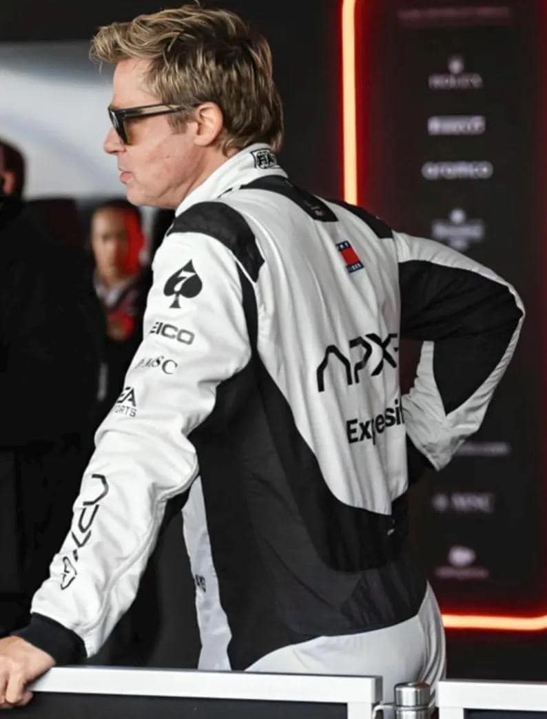 Puede incluir: Chaqueta de carreras blanca y negra con logotipos de patrocinadores en las mangas y la espalda. La chaqueta tiene un logotipo de pica negro en la manga izquierda y la palabra "APX" en la espalda. La chaqueta la lleva una persona con gafas de sol.