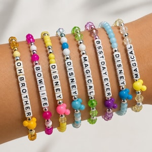 Pode incluir: Oito pulseiras elásticas com contas coloridas, espaçadores prateados e cubos brancos com letras que formam OH BROTHER, BOWLIFE, DISNEY, DISNEY, MAGICAL, BSSTDAYEVER, DISNEY e MAGICAL. Cada pulseira inclui um pequeno pingente em forma de rato.