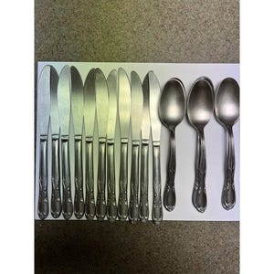 May include: A collection of stainless steel cutlery, comprising knives and spoons, displayed on a white surface. The knives feature a smooth blade and an ornate handle. The spoons have a rounded bowl and a matching handle design. Suitable for meal times.