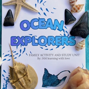 Op de afbeelding: Een wit educatief activiteitenboekje getiteld OCEAN EXPLORERS, FAMILY ACTIVITY AND STUDY UNIT By: JAM learning with love. De kaft bevat blauwe visafbeeldingen, een pijlstaartrogillustratie, een zeester, haaientanden en zeeschelpen.